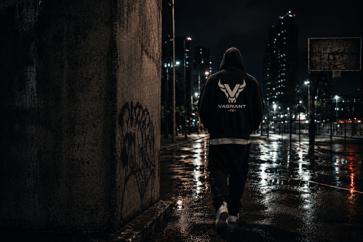 Hooded figure wearing the VAGRANT IV bull logo beside a rain-soaked basketball court at night